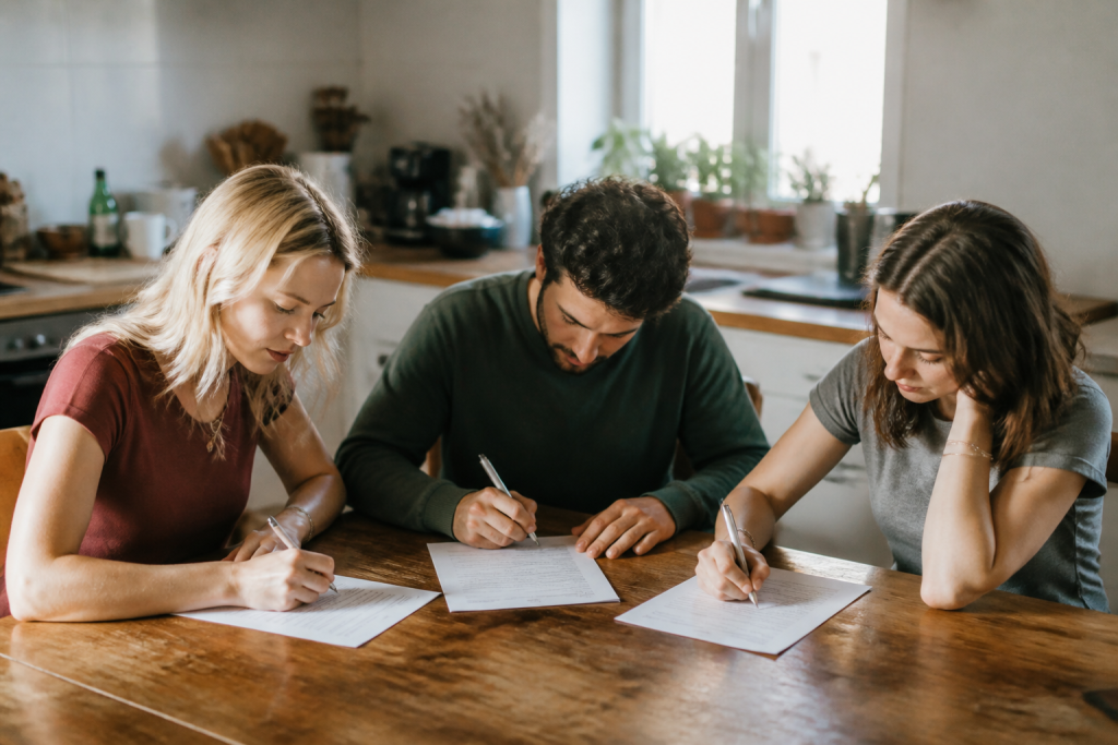 Trois personnes signant des documents de location separate dans cuisine partagee