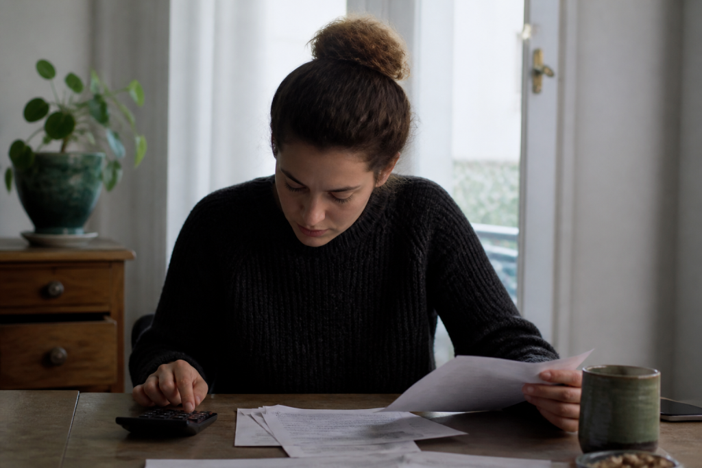 Locataire examinant documents de charges avec calculatrice sur table