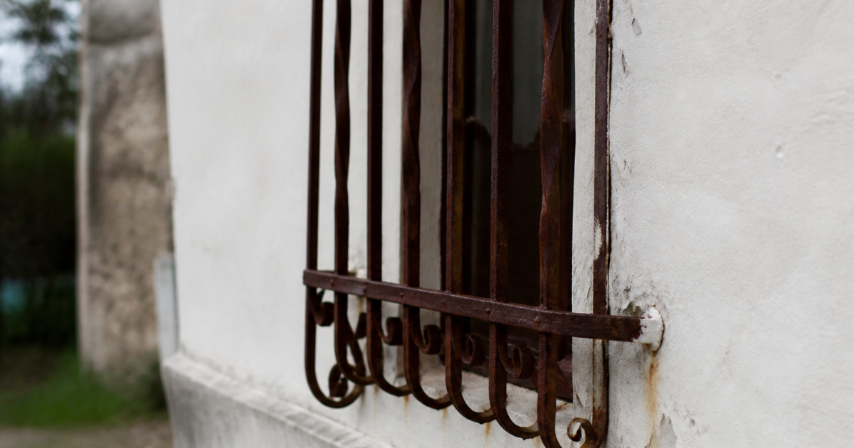 Vieille grille metallique rouille fixee au mur blanc