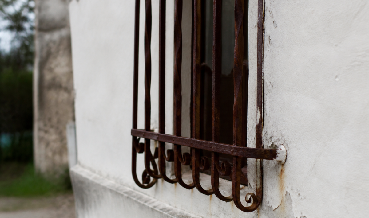 Vieille grille metallique rouille fixee au mur blanc