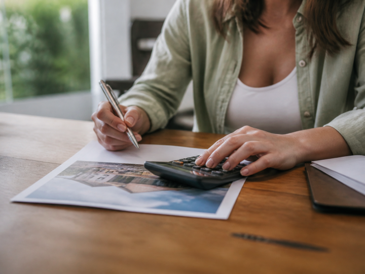 Personne tenant document immobilier avec calculatrice et stylo