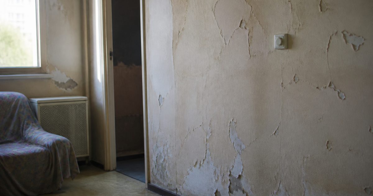 Interieur logement social degrade avec murs fissures et peinture ecaillee