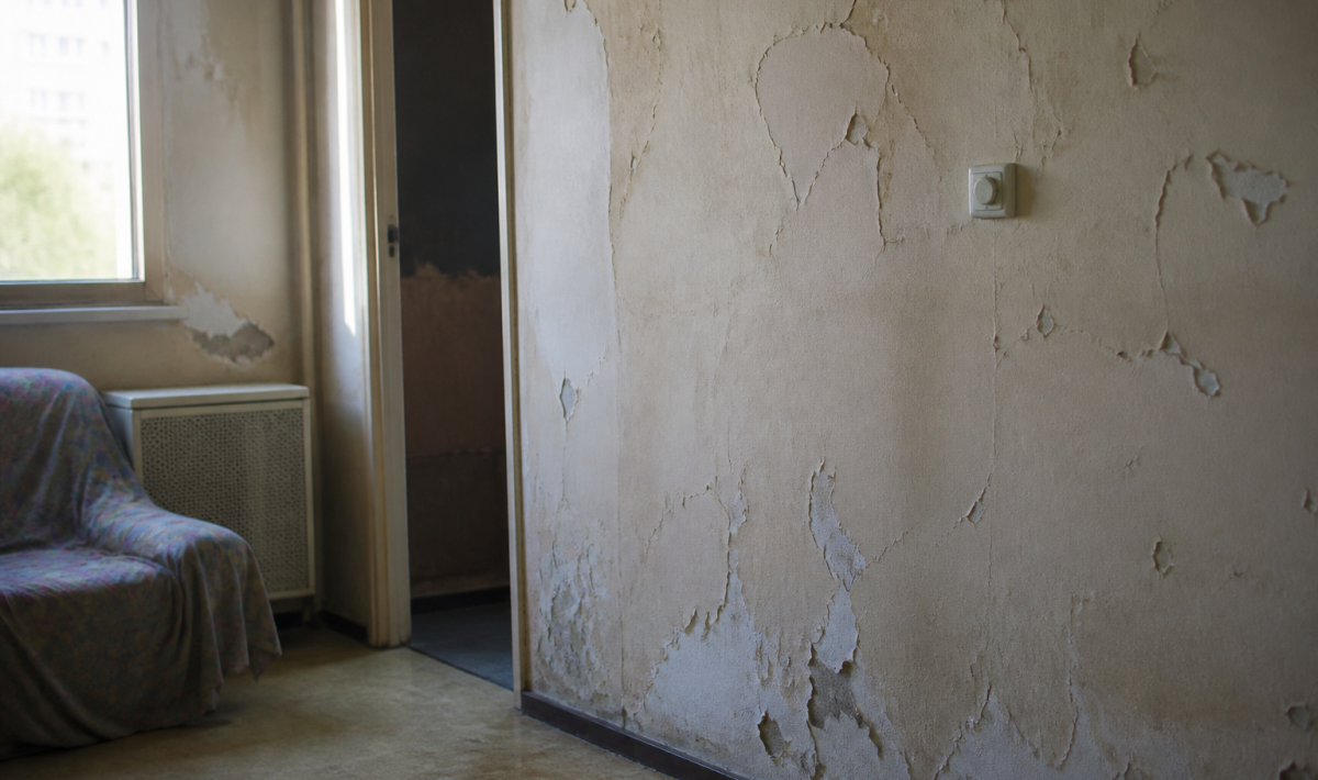 Interieur logement social degrade avec murs fissures et peinture ecaillee