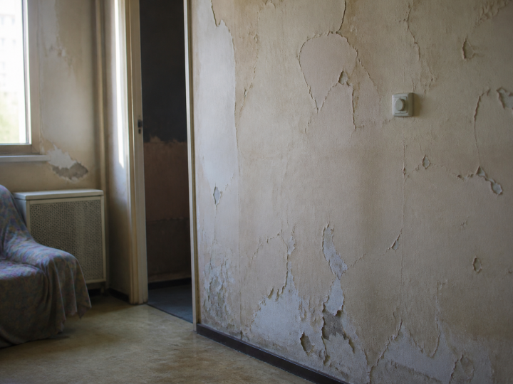 Interieur logement social degrade avec murs fissures et peinture ecaillee