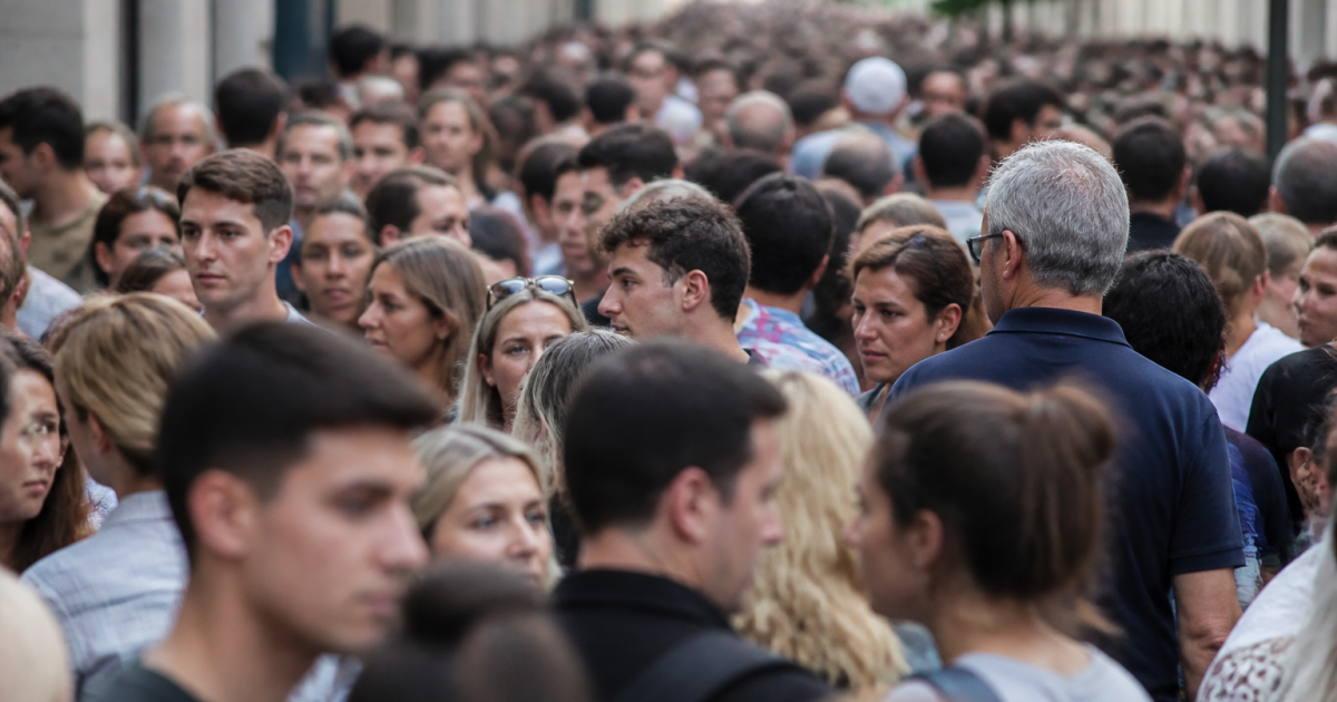 Foule dense de personnes debout serrees dans rue urbaine