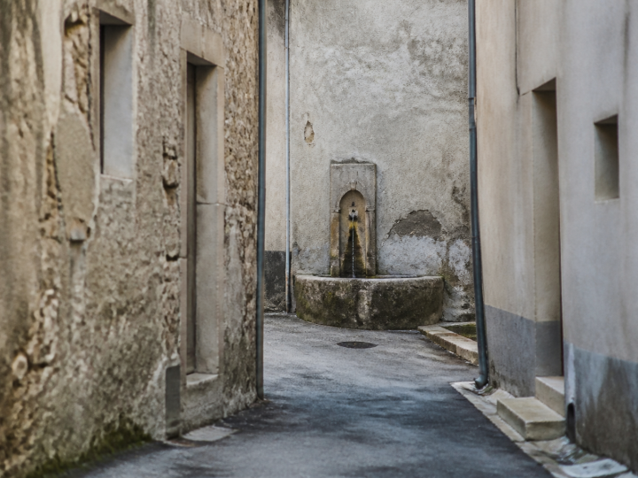 rue etroite fontaine bâtiments délabres murs gris fissurés