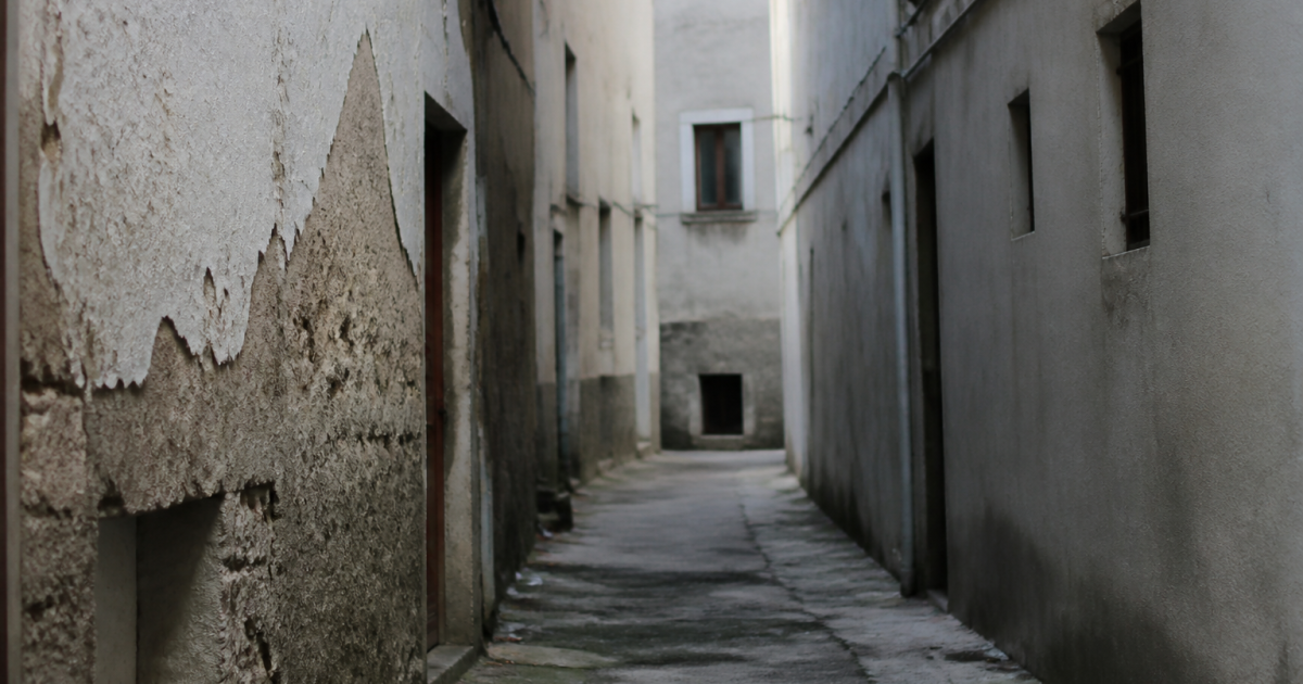 Rue etroite avec immeubles deteriores et facades grises delabrees