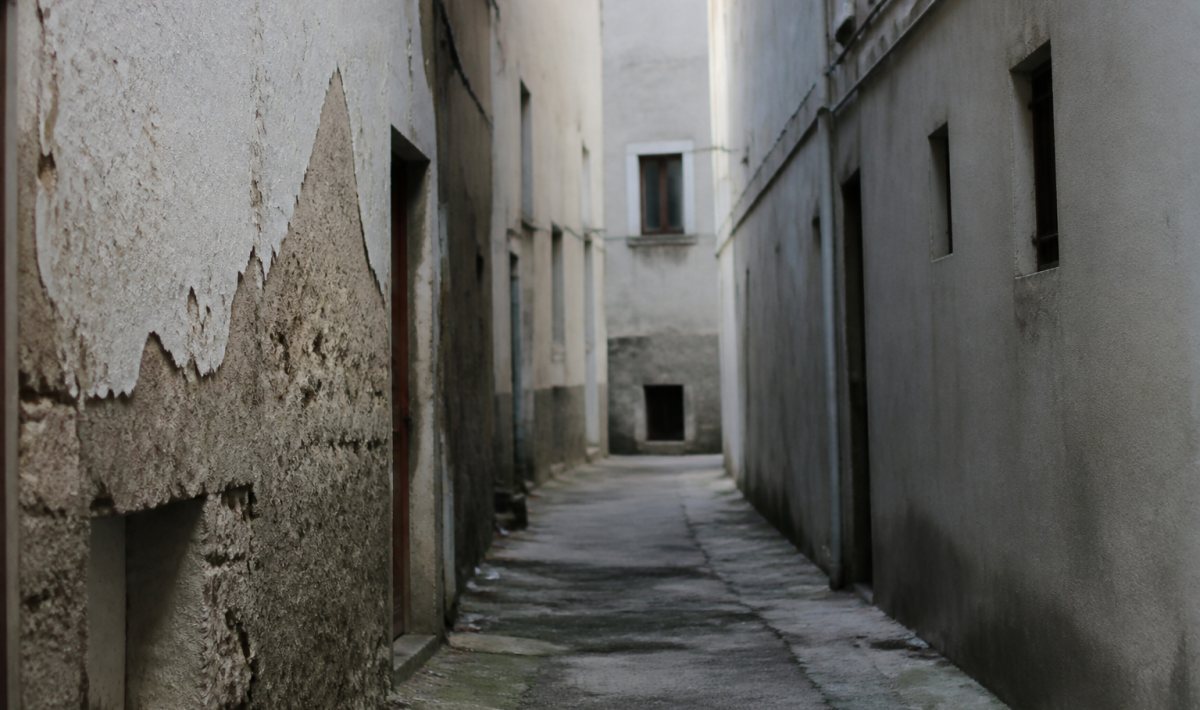 Rue etroite avec immeubles deteriores et facades grises delabrees