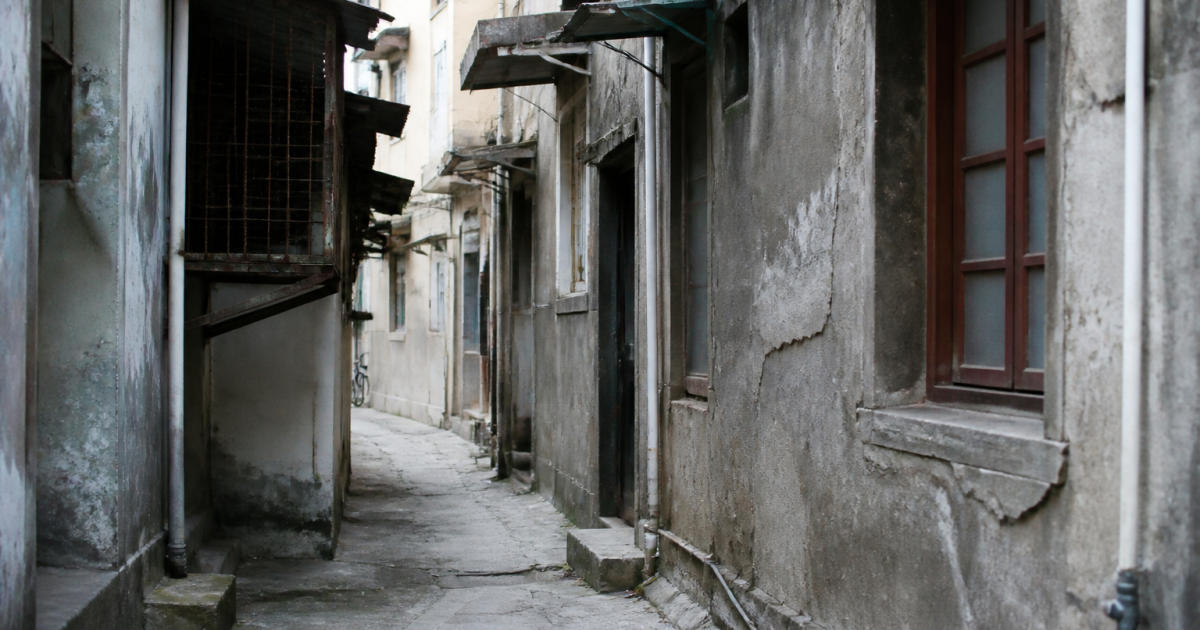 Rue urbaine délabrée avec immeubles gris dégradés et murs fissurés