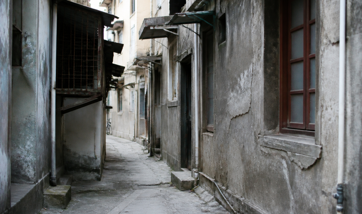 Rue urbaine délabrée avec immeubles gris dégradés et murs fissurés