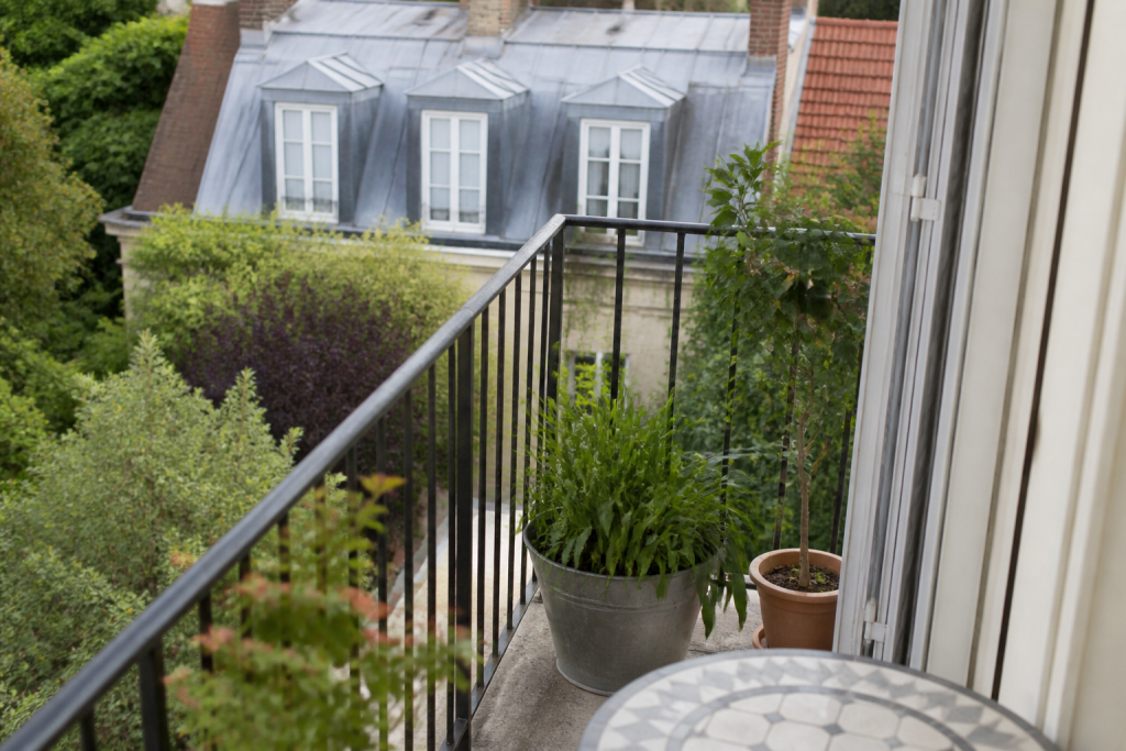 Balcon ouvert, jardin et combles visibles d'immeuble résidentiel